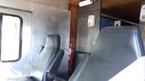 Interior view of a 2004 Freightliner MT45 showing two black leather driver seats and metal wall panels