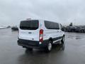 A white 2017 Ford Transit van parked with a rear view showcasing its large windows and black accents