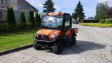 A 2018 Kubota RTV X1100C utility vehicle with an orange and black exterior parked on a paved surface