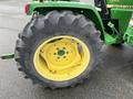 A large rear tire of a 2003 John Deere 790 tractor featuring a yellow rim with a green center and a rugged black tread pattern