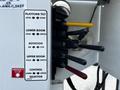 A control panel featuring various levers for platform tilt, lower boom, rotation, and upper boom with labeled functions and a red emergency stop button