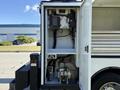 A 2023 Ford F-550 with an open utility compartment displaying various equipment including controls and valves