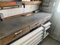 A wooden workbench with several drawers labeled for tools and pipes neatly arranged underneath it