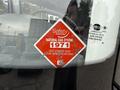 A red and white safety sticker on a vehicle window displaying the text Natural Gas System 1971 and instructions to see the other side for specifications