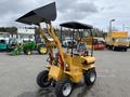 A yellow 2024 AGT Industrial KRW23 Mini Loader with a raised front bucket and a seating area, designed for compact construction and landscaping tasks