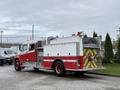 A red and white 2001 Freightliner FL80 fire truck featuring a rear water tank and emergency equipment mounted on the side