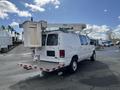 A white 2008 Ford Econoline van with a bucket lift mounted on top and a flatbed rear platform designed for maintenance work