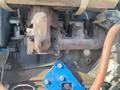 A rusted metal engine component with a bent pipe and several attached hoses on a 1997 Genie S-65 4X4