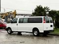 A white 2021 Chevrolet Express van parked on a wet surface with a visible rear and side profile showing its large rectangular shape and tinted windows