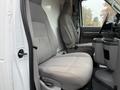 Interior of a 2013 Ford Econoline van featuring two gray cloth seats with armrests and a center console between them