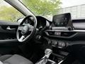 Interior of a 2021 Kia Forte featuring a steering wheel digital display and an infotainment screen with climate control dials