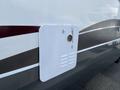 A white exterior access panel on the side of a 2013 Outdoor Wind River with a textured surface and a small ventilation grille at the top