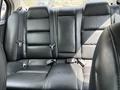 A black leather rear seat of a 2002 Nissan Maxima with seatbelts visible and three seating sections