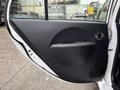 A close-up view of the interior door panel of a 2013 Mitsubishi i-MiEV featuring a circular design handle and speaker at the bottom