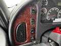 Close-up of the control panel in a 2006 Freightliner M2 112 featuring various buttons and gauges on a woodgrain finish