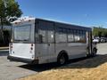 A 2019 Chevrolet Express bus with a gray exterior and large windows is parked with its back facing the viewer