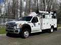 A white 2016 Ford F-550 utility truck equipped with a bucket lift on top and storage compartments on the sides