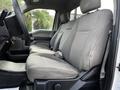 A gray interior of a 2017 Ford F-550 featuring two front seats with fabric upholstery and a center console