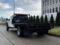 A 2021 Ford F-550 flatbed truck in white with a spare tire mounted on the flatbed and a simple tail light design