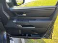 Interior door panel of a 2023 Toyota Tundra featuring a sleek design with control buttons and a handle