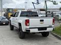 A white 2017 Chevrolet Silverado 1500 pickup truck with a black grille and wheel rims parked with its tailgate open