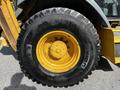 A large yellow and black tire from a 2011 John Deere 310SJ construction vehicle showcasing rugged tread pattern and mounted on a metal rim