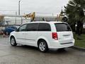 A white 2017 Dodge Grand Caravan is parked with its side facing the viewer displaying a sleek design and modern wheels