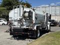 A white 2008 International DuraStar equipped with a large tank and hose attachments located at the rear with a bright orange light on top