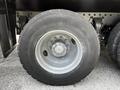 A close-up of a 2010 Freightliner M2 106 truck wheel featuring a silver rim and a black tire with tread patterns