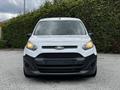 A 2014 Ford Transit Connect in white with a black front grille headlights on and a sleek design