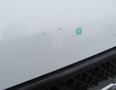 A close-up of a white 2020 Chevrolet Express with a slight blemish visible on the surface near the front grille