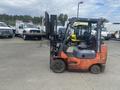 A 2010 Toyota 7FGGU25 forklift with an orange and black color scheme is parked and facing to the right