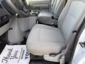 Interior of a 2023 Ford E-450 showing two gray fabric seats with a console between them and a mat on the floor with a thank you message