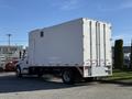 A 2011 Freightliner M2 106 truck in white with a boxy cargo area and dual rear wheels parked at an industrial location
