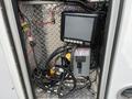 A 2016 Chevrolet Express with various electrical components and wiring visible inside a compartment including a monitor and control panel