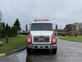 A 2001 Freightliner FL80 truck with a white body and red accents featuring lights on the roof and a prominent front grill