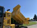 A yellow 2022 TerraMac Tracked Dump with its bed raised in a dumping position showcasing its hydraulic mechanism