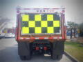 A 2016 International WorkStar 7500 truck with a yellow and black checkerboard reflective sign on the back and a warning message about mirror visibility