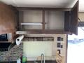 An open overhead cabinet in a kitchen area of a 2016 Jayco 265RLSW with shelves and a roll of paper towels visible below it