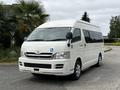 A white 2009 Toyota Hiace with a wheelchair accessibility symbol on the front door and large windows