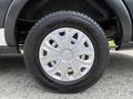 A close-up view of a wheel from a 2021 Ford Transit featuring a silver hubcap and black tire tread