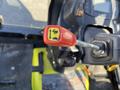 A close-up of an operational control lever with a red handle featuring a yellow illustration of a sideways arrow and an animal silhouette on a Kubota F3990 tractor's dashboard