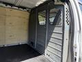 Interior of a 2016 GMC Savana cargo van showing a partition wall with small holes and a wooden wall on the opposite side