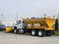 A 2016 International 7600 truck with a yellow plow attached to the front and a large cargo bed for transporting materials