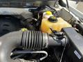 A close-up view of the engine compartment of a 2014 Ford F-150 showcasing various components including the air intake hose and the coolant reservoir