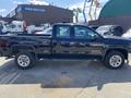 A black 2014 GMC Sierra 1500 pickup truck parked with a crew cab and standard bed visible from the side