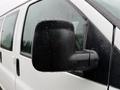 A close-up of the side mirror of a 2021 Chevrolet Express covered in raindrops with a black casing