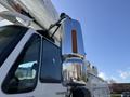 A white 2008 International 7500 bucket truck with a large chrome exhaust stack and a side mirror reflecting its surroundings