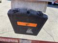 A black storage case with orange markings attached to a metal structure with a visible latch and a worn surface