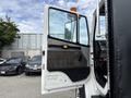 A 1998 Freightliner FL80 with the driver's door open showing the interior details and controls inside the cabin